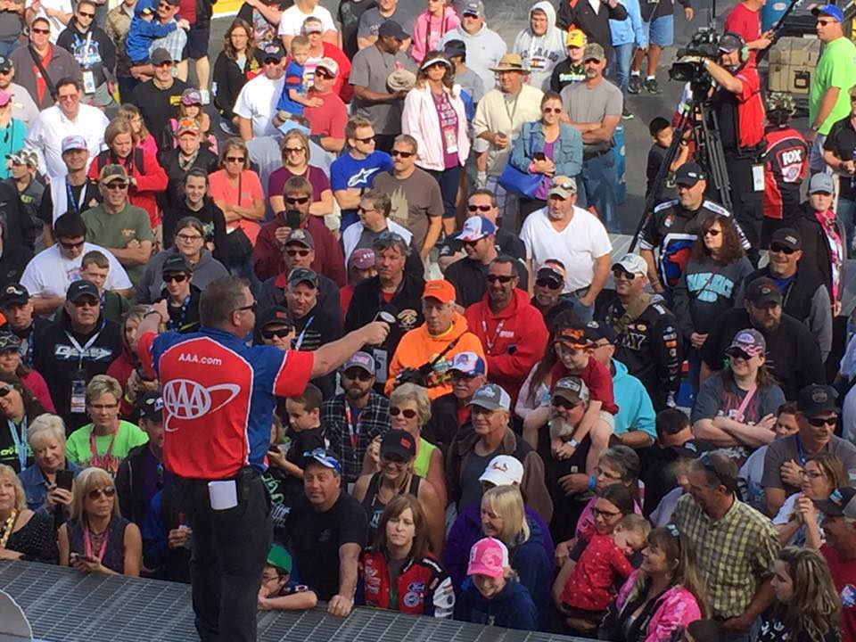 Man speaking to a large outdoor crowd.