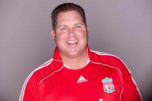 Smiling man in red sports jersey.