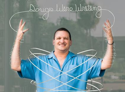 Man posing with wire art around him.
