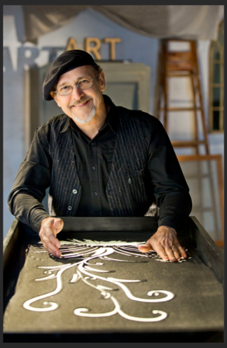 Artist smiling while working on art piece.