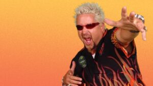 Guy fieri is wearing a black shirt and has white hair.